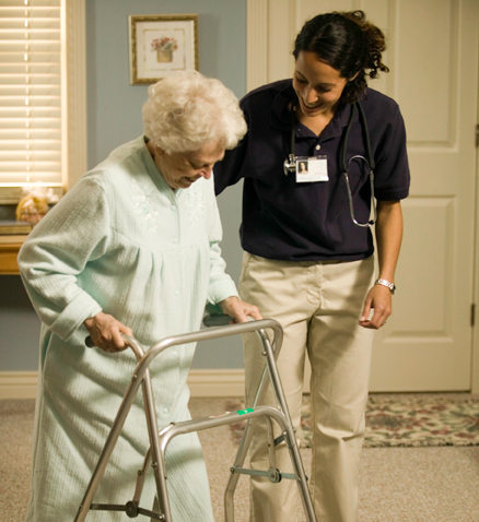 Lady walking on walker with assistance.